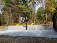 Same spot after concrete court base was installed, with goal system installed in front of wall in Upton, MA.