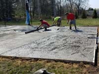 Creating a durable concrete base for a dark green and grey backyard basketball court in Agawam, MA.