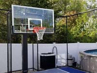 Closeup of hoop and rebound fence for small blue and grey basketball court by existing pool in Braintree, MA.