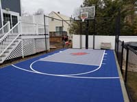 Small blue and grey basketball court in Braintree, MA, adjacent to existing pool and featuring a custom H logo.