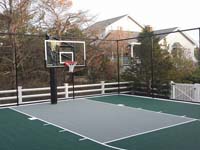 Home basketball court in Plymouth, M, featuring goal system, tall fence, and Versacourt tile surface in green and titanium. Whatever your sport, you could have a court surface and accessories of your own in Dover, Bedford, Cambridge, Acton or Burlington.
