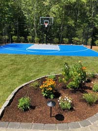 Blue and gray residential basketball court in Easton, MA. We partnered with Evergreen Landscaping of South Easton, whose work is highlighted in the foreground.