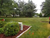 View of lawn where we installed a red and grey home basketball court in Groton, MA.