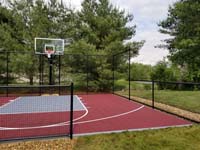 View of red and grey backyard basketball court in Groton, MA.