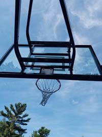 View of goal from below against sky at large royal blue and titanium basketball court with golf seahorse logo at Bay Club in Mattapoisett, MA.