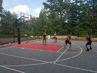 Young adults playing basketball on rebuilt town court in Plympton, MA.