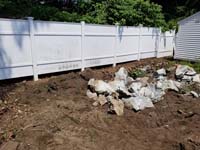 Rocks from broken boulder, awaiting removal to make way for royal blue and yellow basketball court and accessories in Stoneham, MA.
