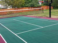 Backyard basketball court in Sudbury, MA, made to use for tennis and volleyball, giving more bang for the court purchase buck.