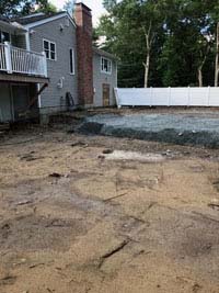 Filled in site of dead pool that will be replaced be a graphite and orange basketball court in Walpole, MA.