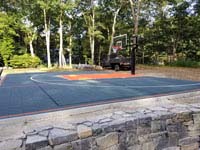 Graphite and orange backyard basketball court where there was previously a pool in Walpole, MA.