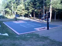 Full view of graphite and rust backyard basketball court on tar base in Walpole, MA.