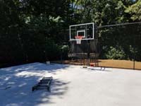 Durable concrete base is ready for low impact tile installation for black and grey home backyard basketball court in Wellesley, MA.